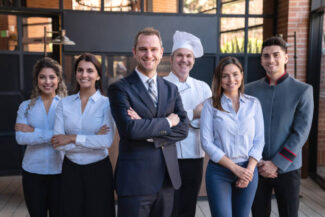 Cheerful latin american team of hotel staff all facing camera smiling  - Business concepts